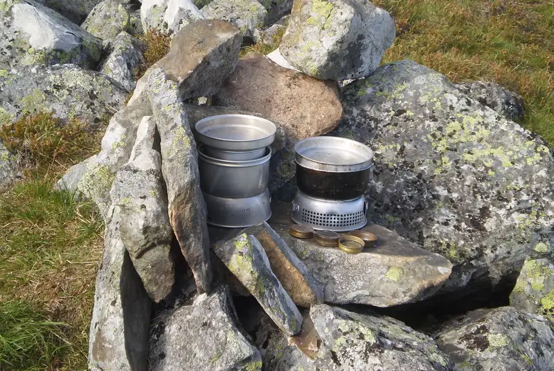 Två Trangia-stormkök på en stenhäll mellan lavklädda stenar